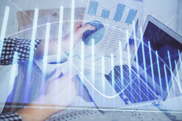 Forex graph with businessman working on computer in office on background. Concept of hardworking. Multi exposure.