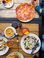 dinner on wooden table: Eating foods (Salad with shrimps, soup with sea food, pizza, salad with chicken, lasagna, french fries) and drinks (coctail, juice beer). Food Background. enjoy eating concept