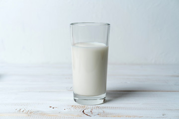 glass of milk on white wooden table, copy space for recipe or product composition
