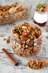 Granola with different nuts in a glass jar on the white wooden table