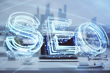 Double exposure of table with computer and seo drawing hologram. Search optimization concept.