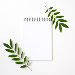 Marble paper blank, Notepad on white background. Flat lay, top view, copy space. Green leafs and blank notepad.