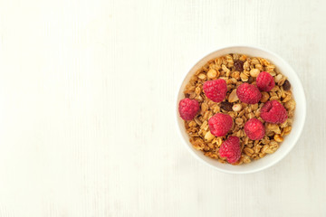 Oatmeal porridge with raspberries and nuts in bowl on white table, top view