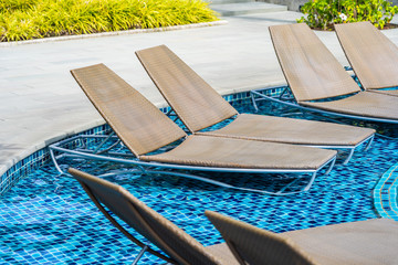 Empty chair for take a seat and relax around outdoor swimming pool in hotel resort for holiday vacation