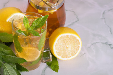 Glass of iced tea with mint and lemon on marble table. Cold drink.