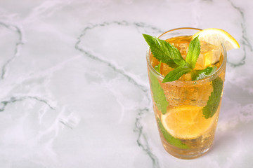 Glass of iced tea with mint and lemon on marble table. Cold drink.
