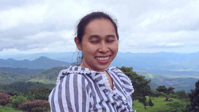 Asian woman looking at beautiful scenery and smile to camera at Huai nam dang national park; Pai, Chiang Mai, Thailand.