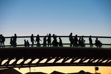 Silhouette of walking people on bridge at sunset