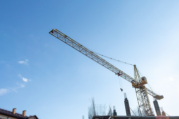 Fototapeta na wymiar Tower crane on the blue sky background. Building construction work concept, investments in the development construction buildings and structures industry.