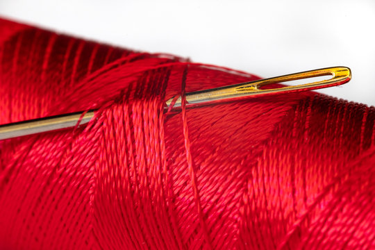Macro image of needle and red thread on white background