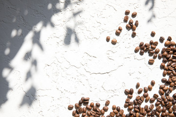 Lots of coffee beans loose on a white textured background. The concept of good morning.