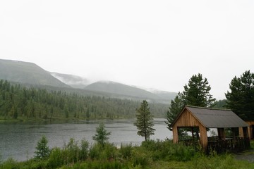 Fototapeta premium low clouds and fog over the lake in the mountains with wooden house
