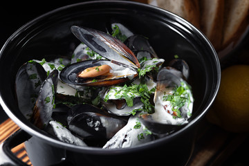 Boiled mussels with a sauce in a black pan