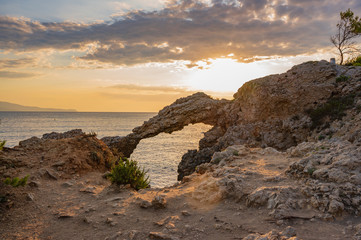 Sunrise with the sun streaking through the natural rock formation on the coast at L'Escala...