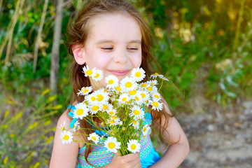 Sute kid girl holding a bouquet of daisies on a Sunny summer day. Mother's day. Family day. Concept of summer vacation.