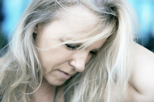 Attraktive reife Frau mit blonden Haaren in Gedanken versunken