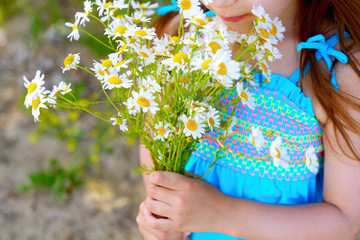 Happy child girl holding a bouquet of daisies on a Sunny summer day. Mother's day. Family day. Concept of summer vacation.