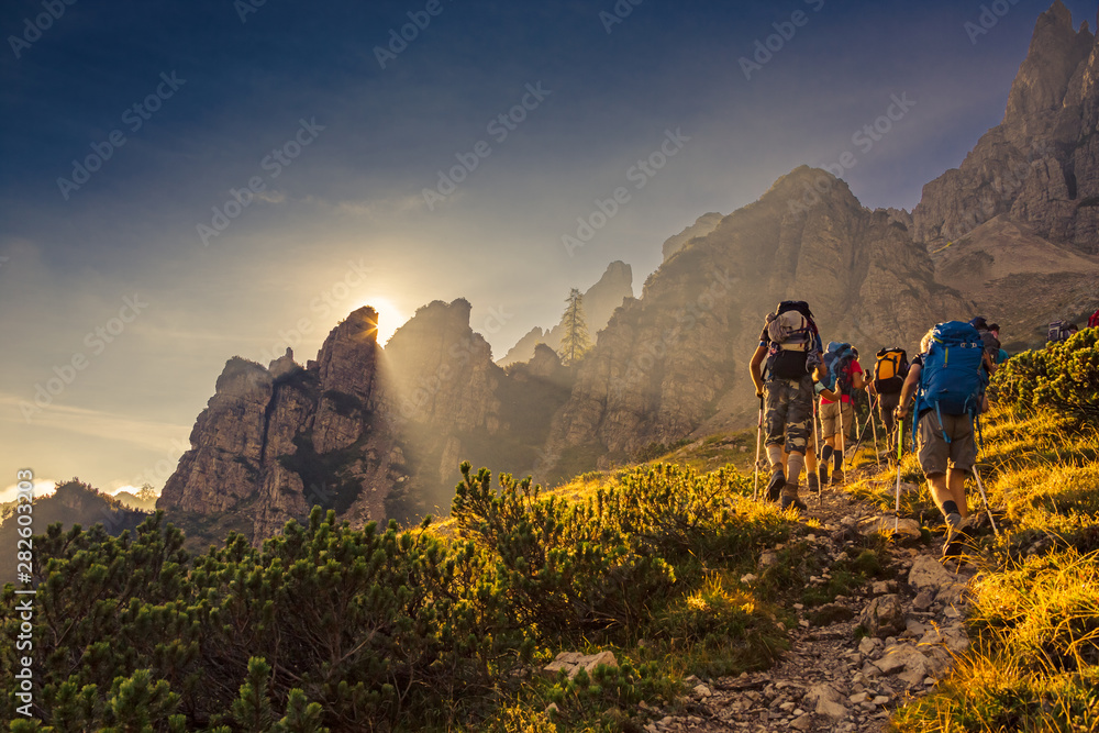Wall mural some hikers go up a mountain path in the early hours of the day