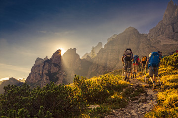 Some hikers go up a mountain path in the early hours of the day - obrazy, fototapety, plakaty
