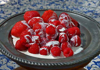 Close up of a decorative pewter platter with raspberries, strawberries and cream