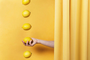 Conceptual still life composition of woman's hand reaching from behind the yellow curtain and...