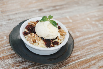 Apple crumble dessert with vanilla ice cream on the top on wooden table