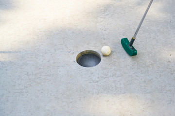 Fototapeta na wymiar mini golf club hits the ball into the hole on a track from concrete, copy space