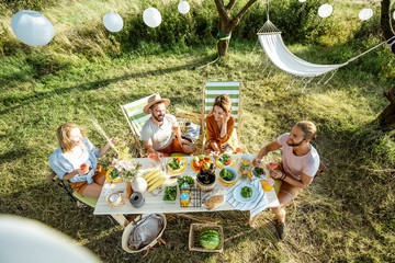 Group of a young friends having festive lunch in the beautifully decorated garden on a summer...
