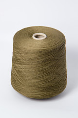 Green bobbin of yarn on a white background.Textile reel on isolated white background.