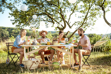 Group of a young friends having festive lunch in the beautifully decorated garden on a summer...