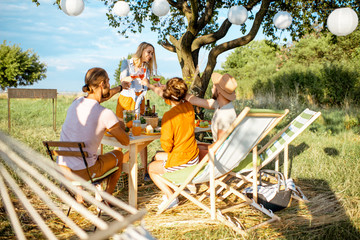 Young people having festive lunch in the beautifully decorated garden with hammock and garland on a...