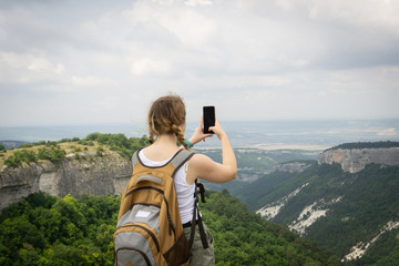 girl traveler photographs a beautiful view on the phone