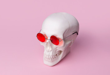 Skull in sunglasses on pastel pink background.