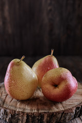 Juicy pears beautifully lit by light in low key on a dark background are on a wooden desk, vertical orientation