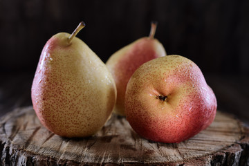 Juicy pears beautifully lit by light in low key on a dark background are on a wooden desk, close up