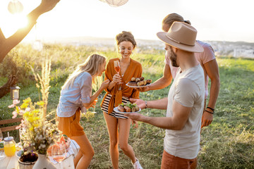 Group of a young and happy friends having fun during a festive picnic in the beautifully decorated...