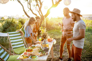 Group of a young and happy friends having fun during a festive picnic in the beautifully decorated...