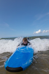Little boy learning to surf at the beach, getting up on surfboard for the first time, west coast of...