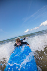 Little boy learning to surf at the beach, getting up on surfboard for the first time, west coast of...