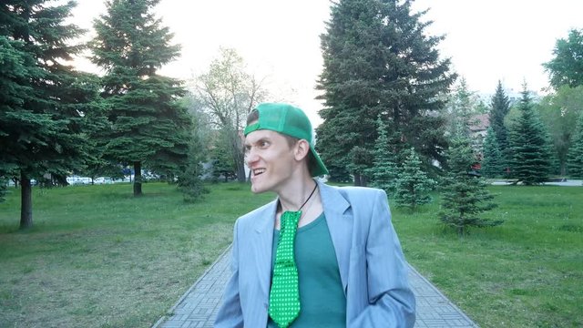 Crazy guy builds faces on camera.  Guy clown laughs and moves funny and smiles. He wears jacket, green tie, and vest. He is freak.