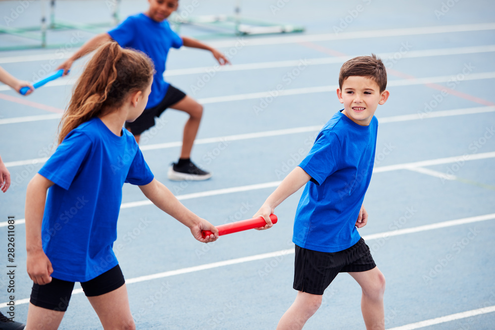 Wall mural children in athletics team competing in relay race on sports day