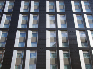 view of the facade of a large black and white modern commercial building with repeating windows and geometric panels