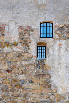 Vertical frame of two windows on an old rough acient medieval stone wall at Varberg Fortress in Sweden.
