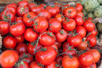 red fresh tomatoes on branch in wicker baskets on counter