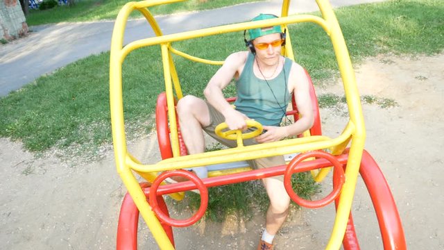 Boy and car.  Guy sits in car in the yard of the child garden and grimaces portraying driving a car.