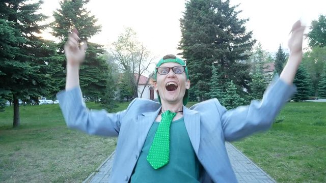 Crazy guy builds faces on camera.  Guy clown laughs and moves funny and smiles. He wears jacket, green tie, and vest. He is freak.