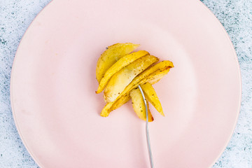 French fries. Homemade, roasted french-fried potatoes. Top above view on table. Junk food. On plate with fork.