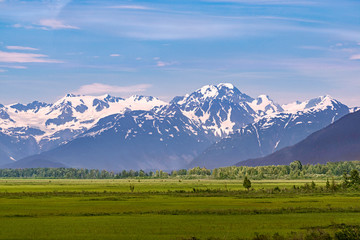 pastoral panorama of the chugach mountains and forest southeast of anchorage alaska with green meadows in the foreground