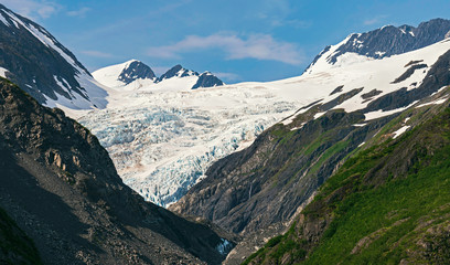 closeup of an alaskan glacier near portage and whittier surrounded by mountains with blue sky and puffy clouds in the background