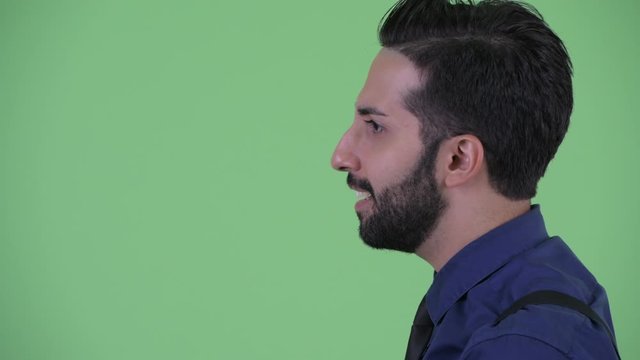 Closeup profile view of happy young bearded Persian businessman talking